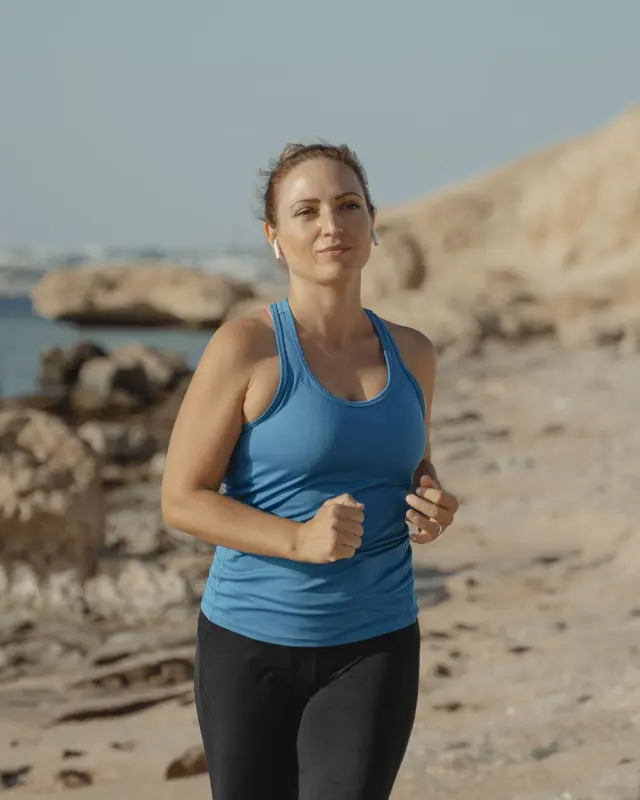 Mulher a correr numa praia, com saúde e energia
