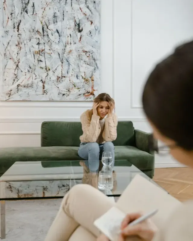 Paciente numa sessão de psicologia, sentada no sofá enquanto a psicóloga toma notas